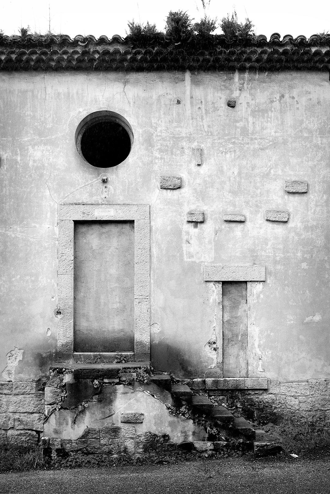 A raised door and a circular window on a facade.